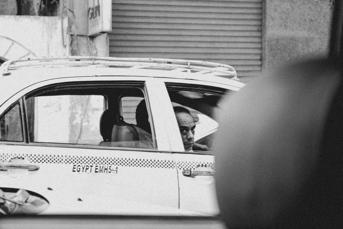 A passenger looking through a taxi window in a street scene