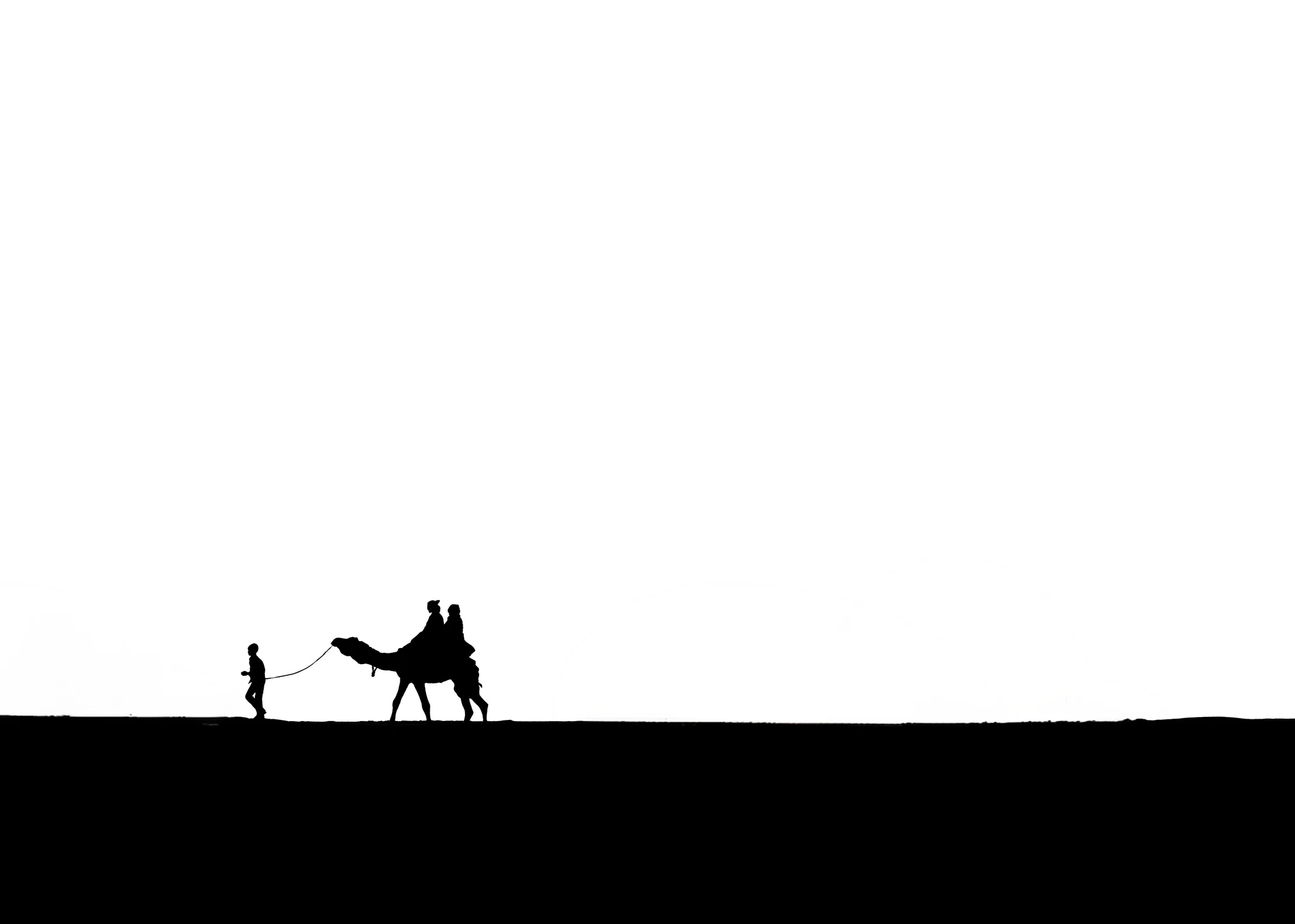 A child leading a camel across a minimalist black-and-white horizon, photographed by Priya Ojha