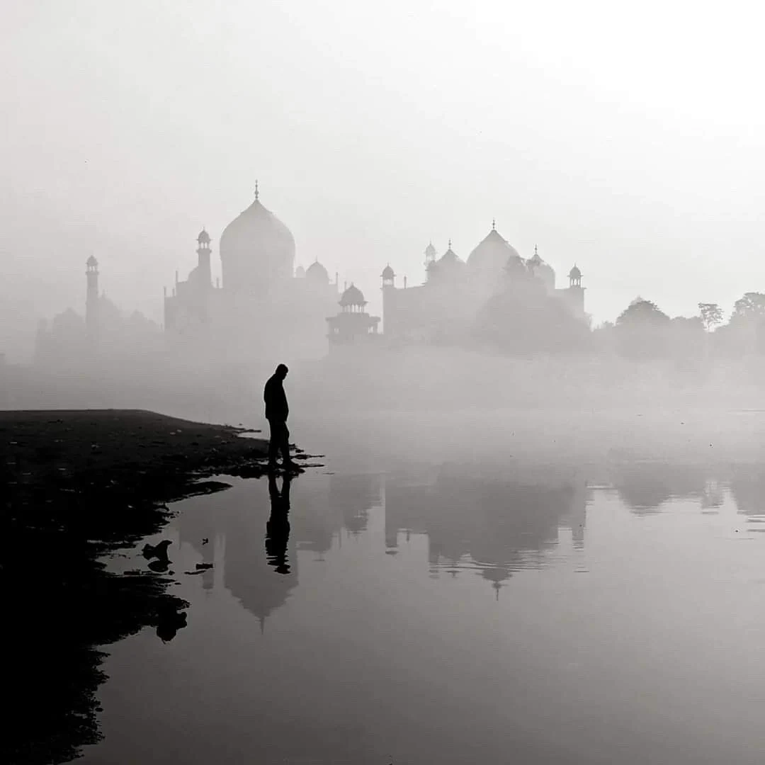 A solitary figure beside the reflected silhouette of the Taj Mahal, photographed by Priya Ojha