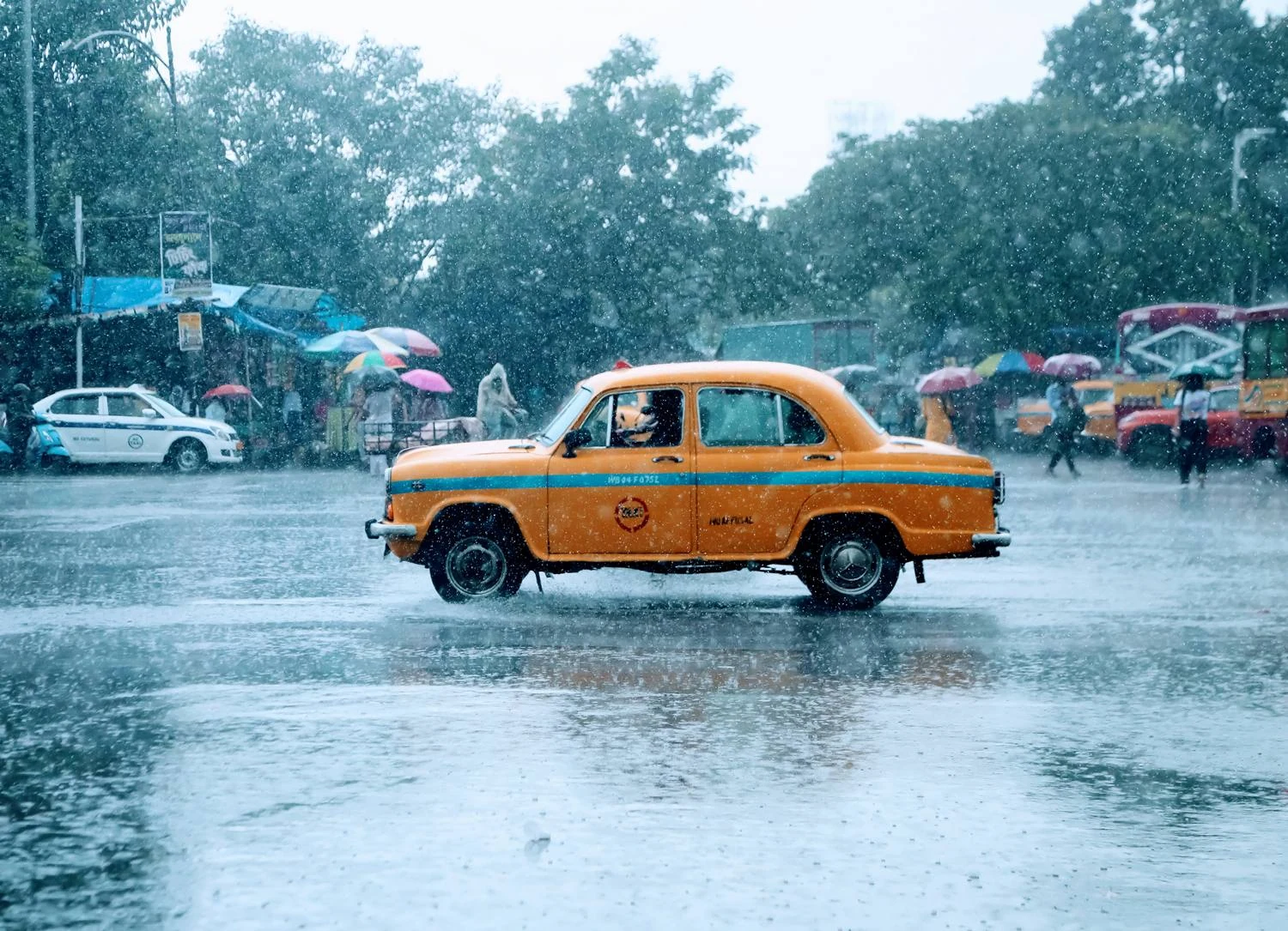 A yellow taxi crossing a city street in heavy rain, photographed by Priya Ojha