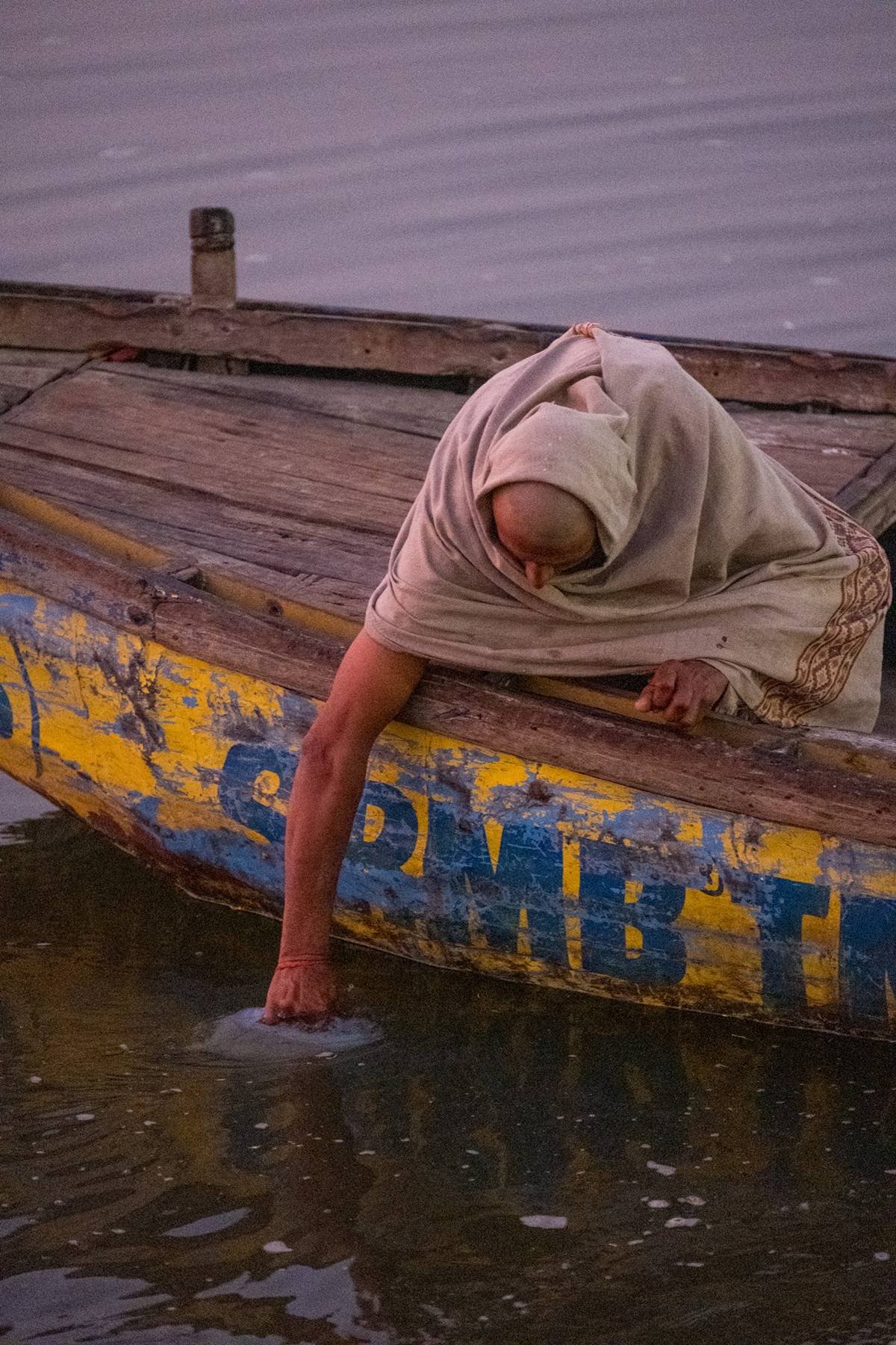 A woman reaching into the water from a boat