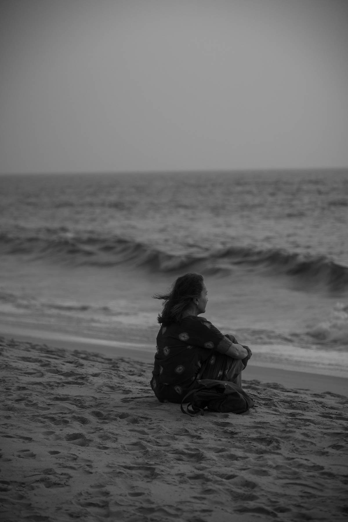 A lone figure seated by the sea