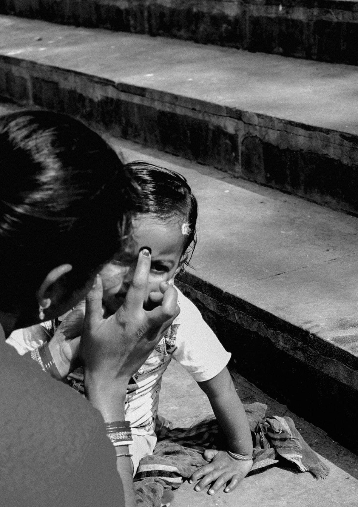 A child shielding her face beside stone steps