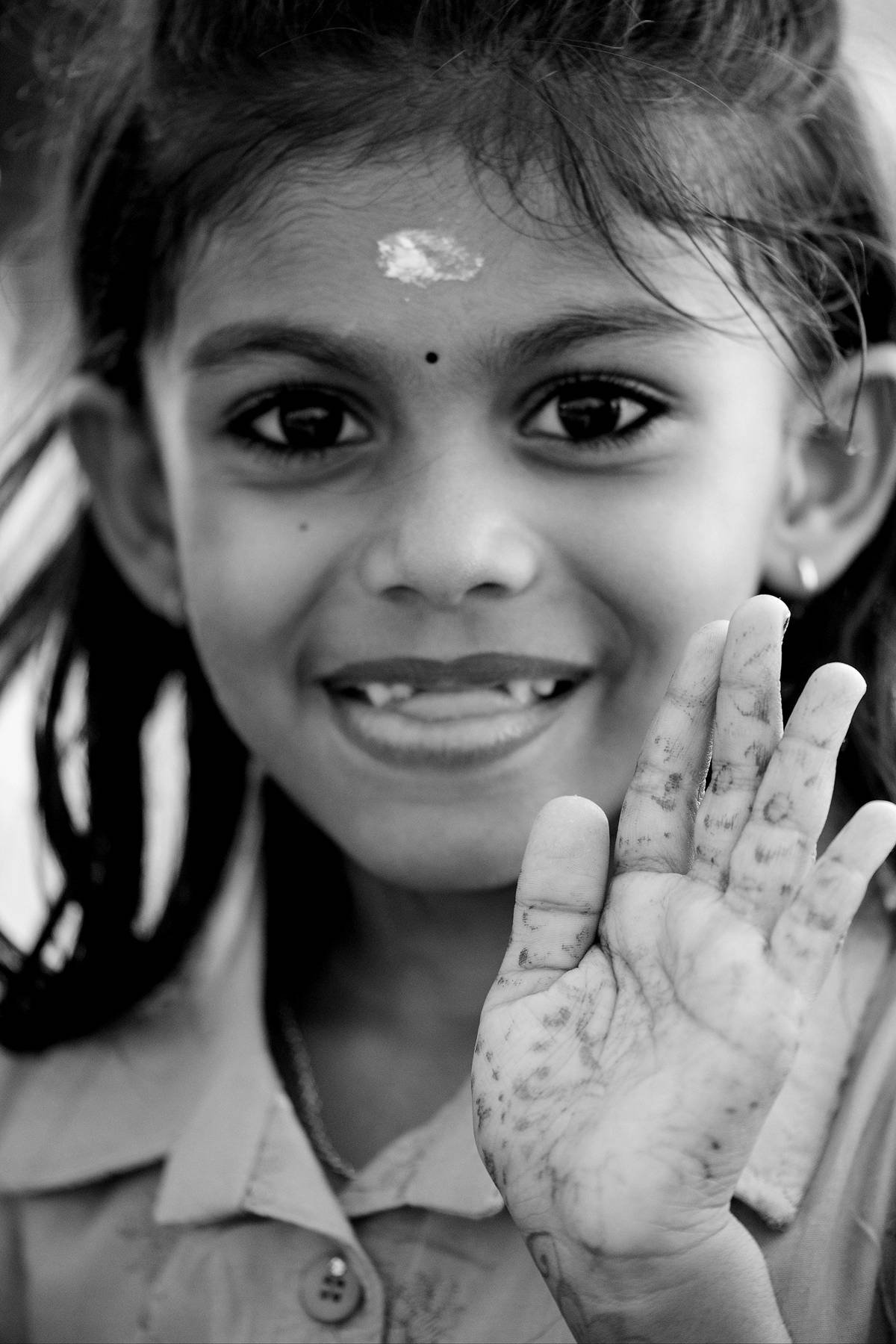A smiling child raising her hand toward the camera