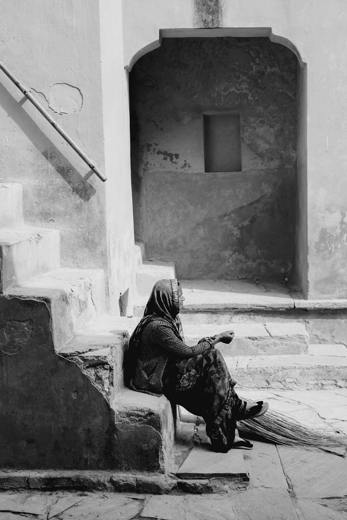 A woman sitting alone in a sunlit courtyard